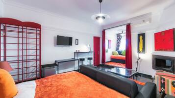 Una habitación de hotel moderna con una cama grande, un escritorio, un televisor y un sofá.