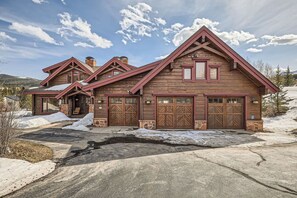 Une grande maison en bois avec plusieurs portes de garage, des fondations en pierre et un ciel dégagé.