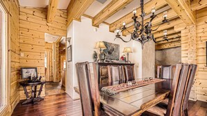 Une salle à manger en bois avec une grande table, des chaises et un lustre.