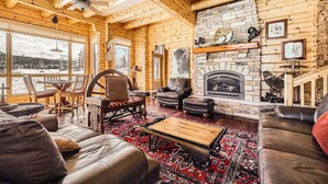 L’intérieur d’un chalet en bois, avec une cheminée, des meubles en cuir et une vue sur le paysage enneigé.