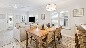 A dining area with a wooden table, wicker chairs, and a ceiling fan. - Community Pools | LSV | Close to Beach (Santa Rosa Beach)