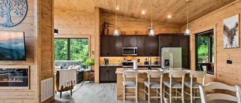 A spacious wooden cabin interior with a dining area, kitchen, and living room.