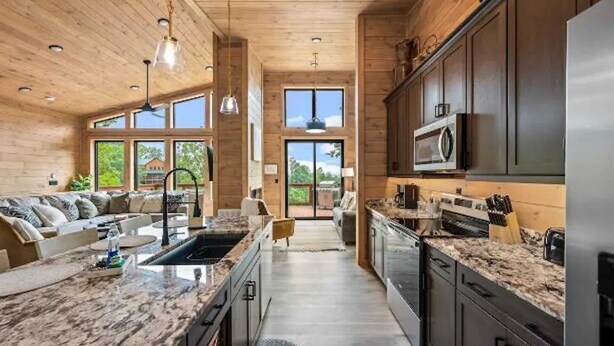 A modern kitchen with a large island, dark cabinets, and a microwave. - Stunning Cabin for 6 with Hot Tub & Pool Table! (Sevierville)