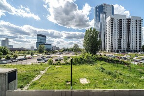 A cityscape with modern high-rise buildings, a parking lot, and a grassy area. - RentPlanet - Apartament Góreckiego (Katowice)
