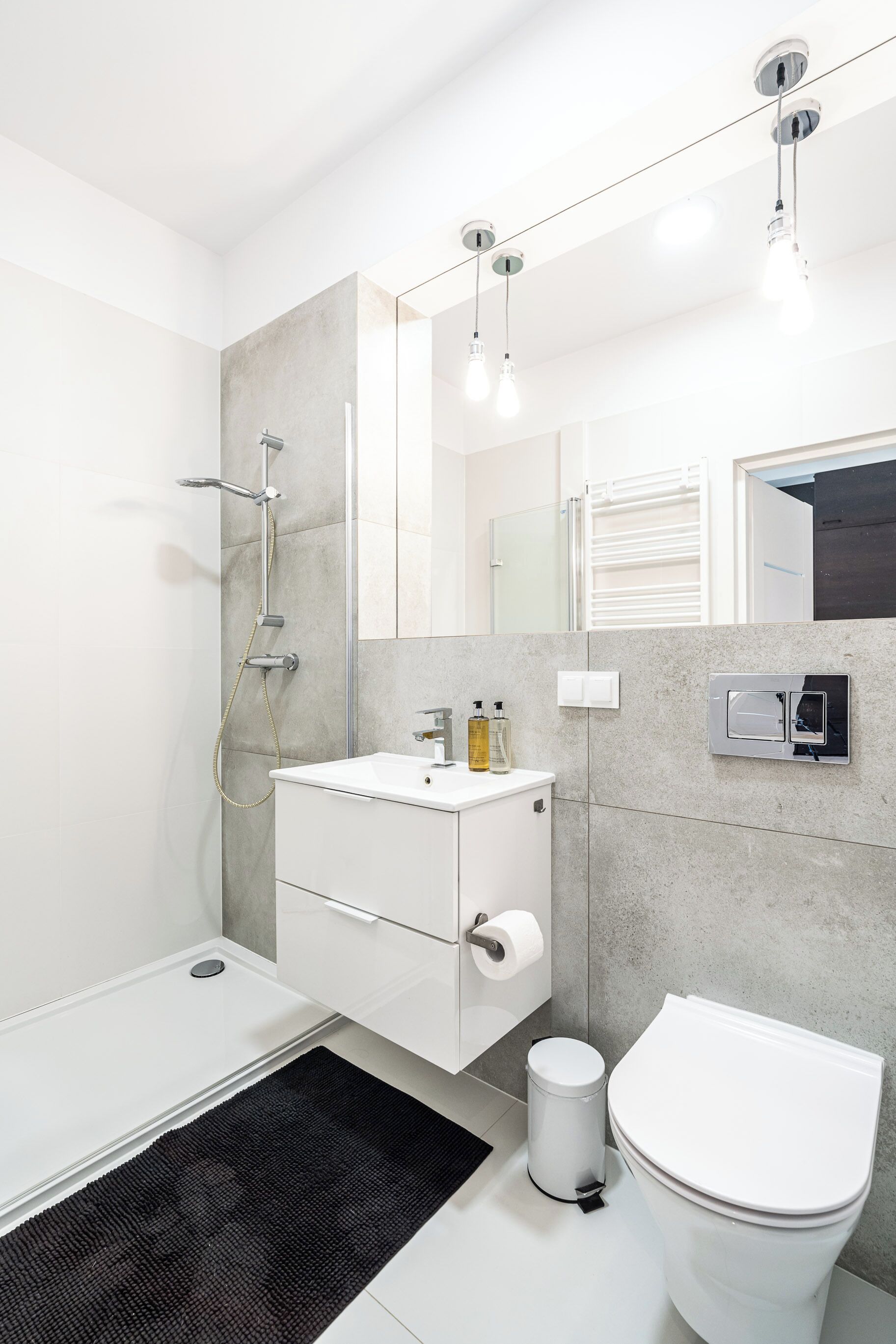 A modern bathroom with a shower, toilet, sink, and mirror.