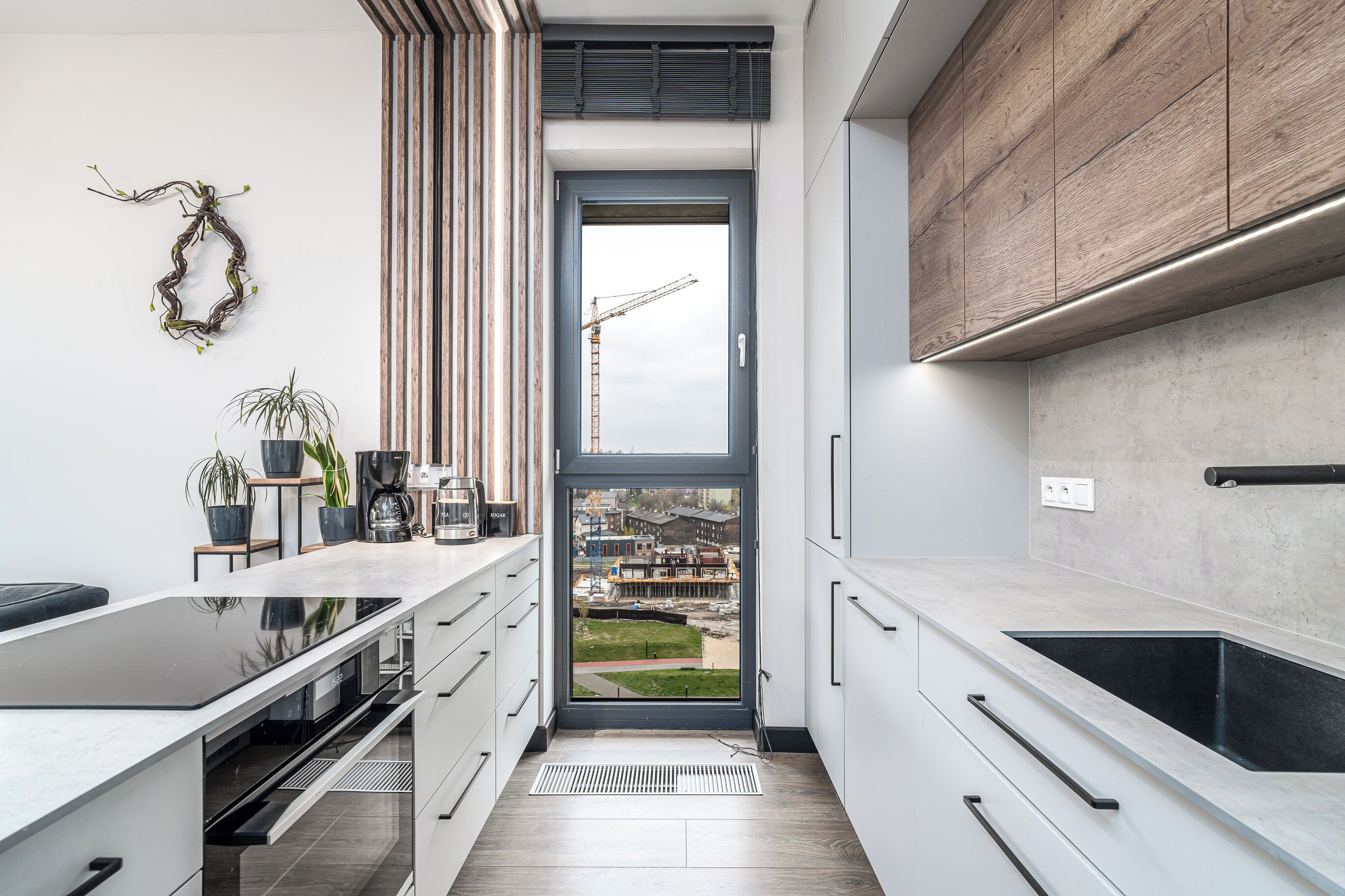 Una cocina moderna con un ventanal grande, armarios empotrados y vistas a una obra en construcción.