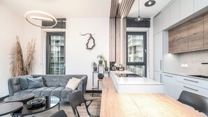 Une cuisine moderne dotée d’un îlot central, d’un coin repas avec une table et des chaises en bois, et d’un canapé gris accompagné d’une table basse.
