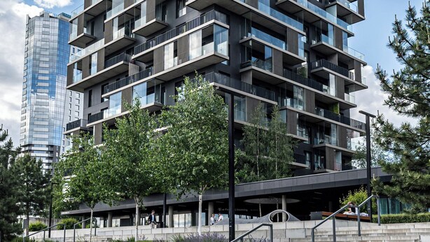 Un immeuble à plusieurs étages doté de balcons, d’un escalier et entouré d’un espace paysager aménagé.