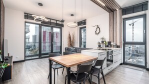 Une cuisine moderne avec une table et des chaises en bois, un four encastré et une grande fenêtre donnant sur la ville.