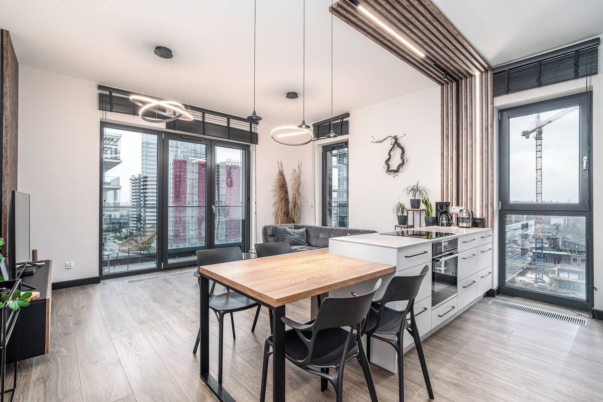 Una cocina moderna con una mesa y sillas de madera, horno empotrado y un ventanal con vista a la ciudad.