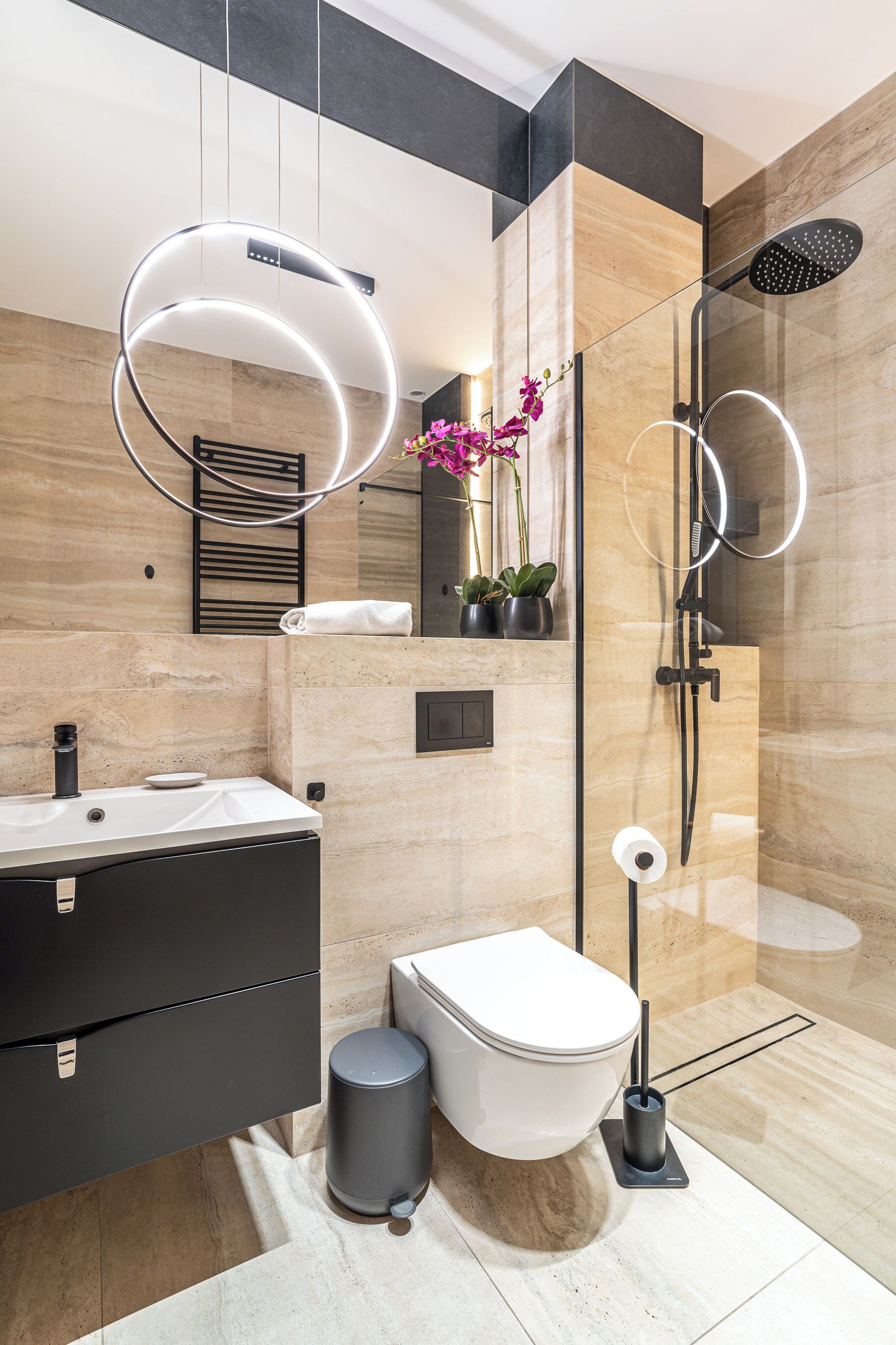 A modern bathroom with a toilet, bidet, and shower. There is a vanity with a mirror and a towel rack.