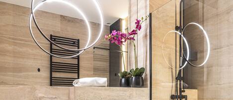 A modern bathroom with a toilet, bidet, and shower. There is a vanity with a mirror and a towel rack.