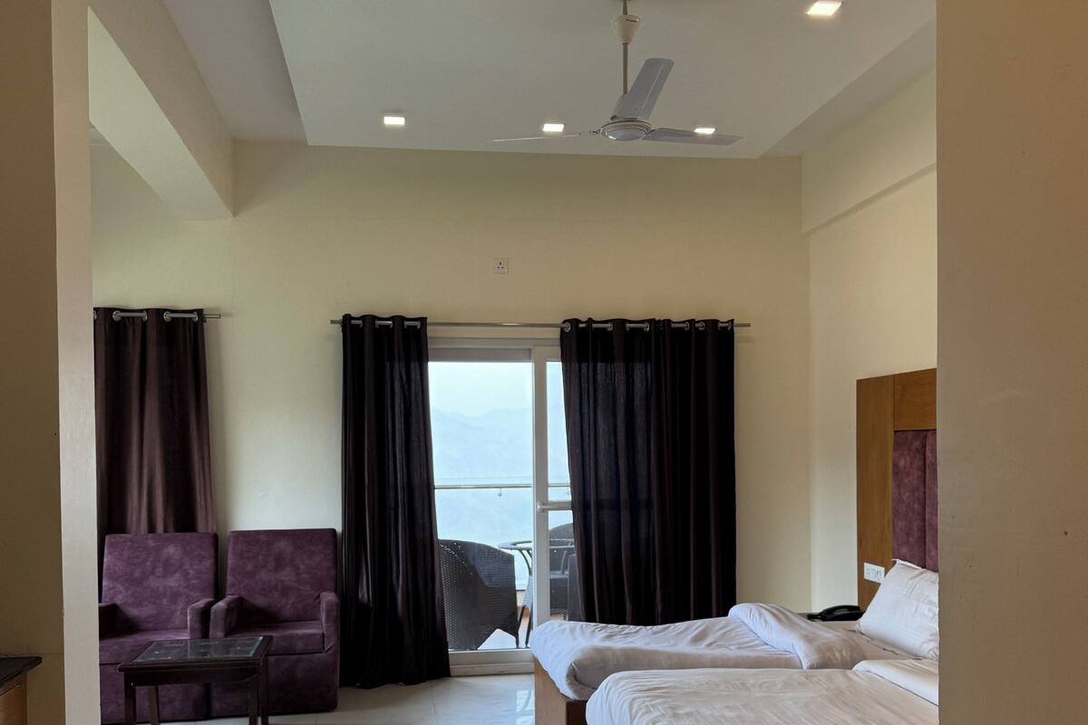 A hotel room with a bed, a chair, a table, and a view through a window.