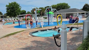 A swimming pool area with multiple water features, lounge chairs, and a covered seating area. - Coastal Camelot - Walk To Surfside Beach 2 Bedroom Duplex (Murrells Inlet)