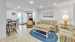 A spacious living room with a dining area, a sofa set, a coffee table, and a lamp. - Coastal Camelot - Walk To Surfside Beach 2 Bedroom Duplex (Murrells Inlet)