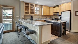 A modern kitchen with a large island, bar stools, wooden cabinets, and built-in appliances. - Fantastic Mountain Home Near Ski Lifts 3 Bedroom Condo (Keystone)