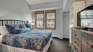 A bedroom with a bed, a dresser, a television, and windows. - Fantastic Mountain Home Near Ski Lifts 3 Bedroom Condo (Keystone)