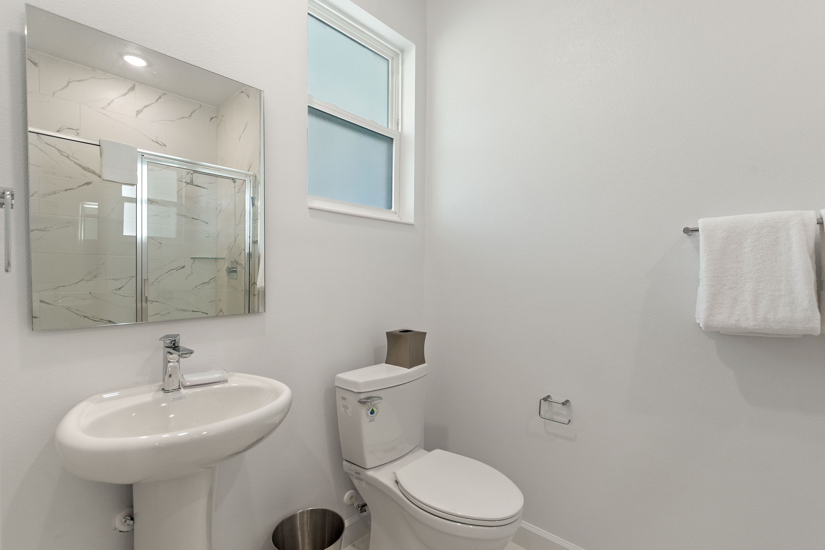 Une salle de bain avec un lavabo blanc, des toilettes et un miroir.