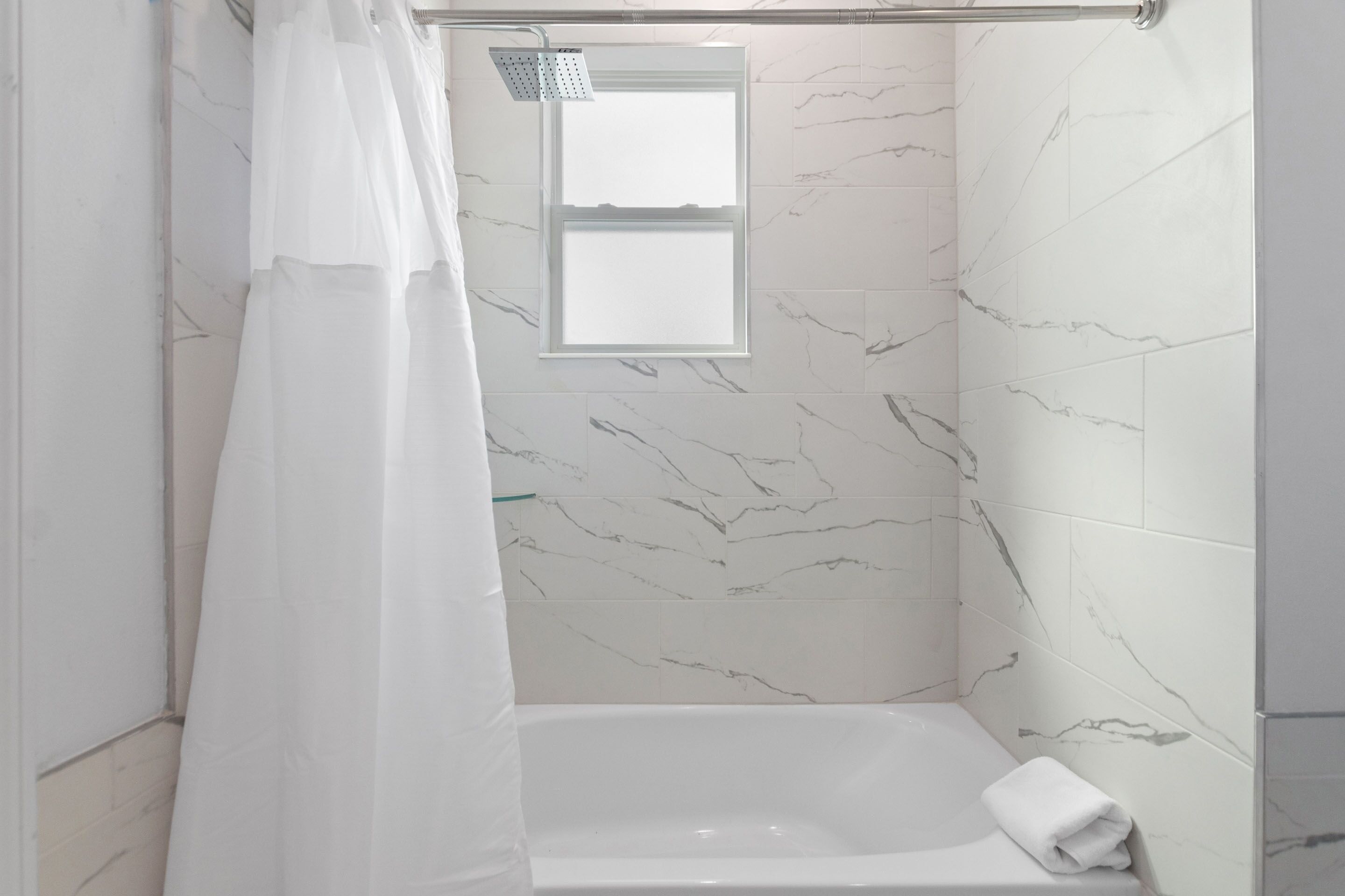 A bathroom with a shower, a window, and a bathtub.