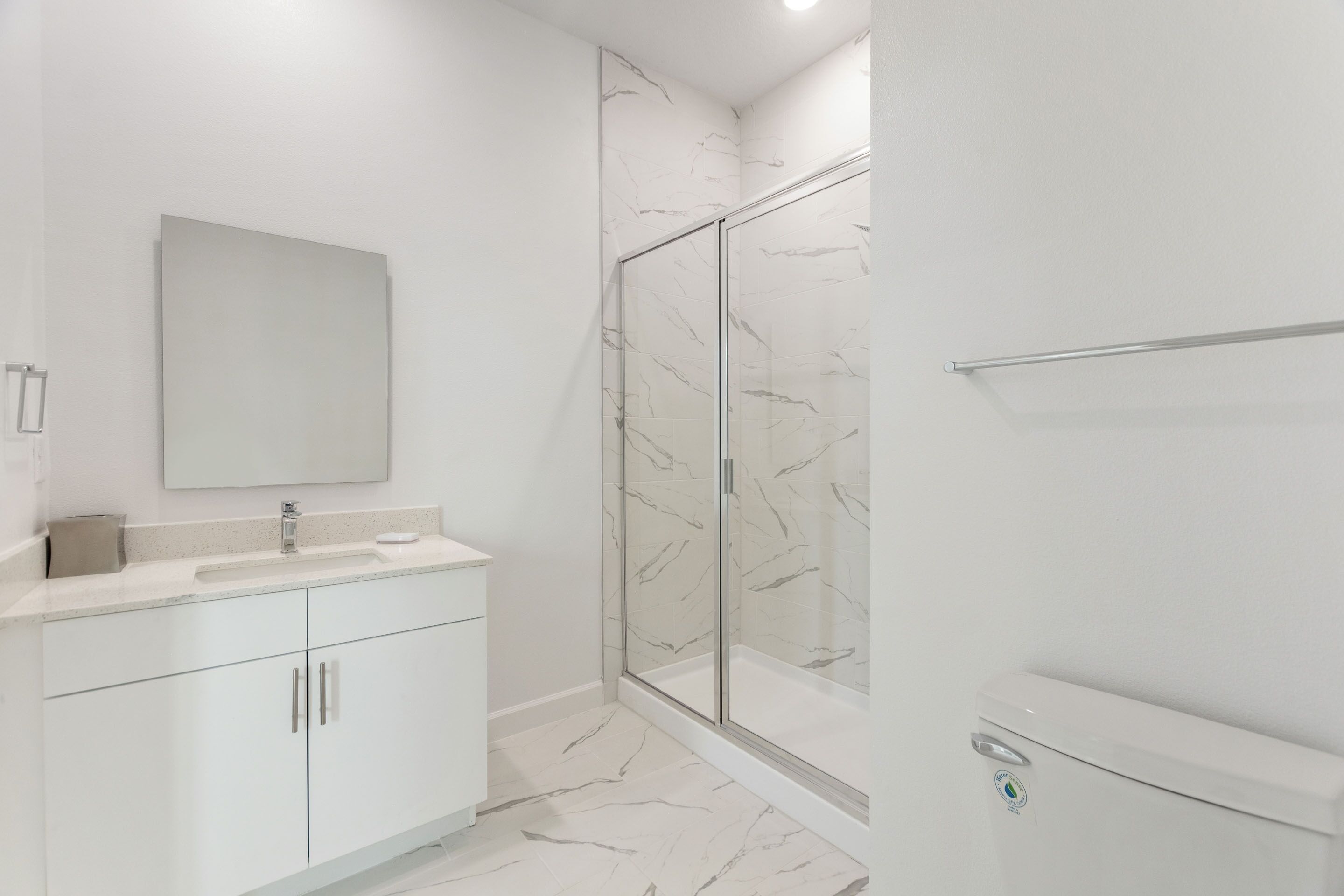 A modern bathroom with a glass shower enclosure, a white sink, and a large mirror.
