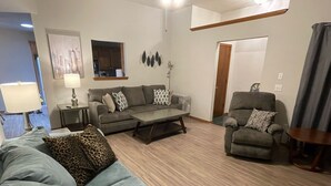Ein Wohnzimmer mit Sofa, Sessel, Couchtisch und einem Esstisch mit Stühlen.