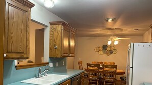 Eine Küche mit Holzausstattung, einem Spülbecken, einem Esstisch mit Stühlen, einem Kühlschrank und einem Deckenventilator.