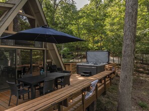 A deck with outdoor seating, a hot tub, and a large umbrella.