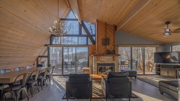 A spacious living area with a wooden ceiling, a fireplace, and a large TV. - Whitetail Creek Retreat by Innsbrook Vacations! (Innsbrook)