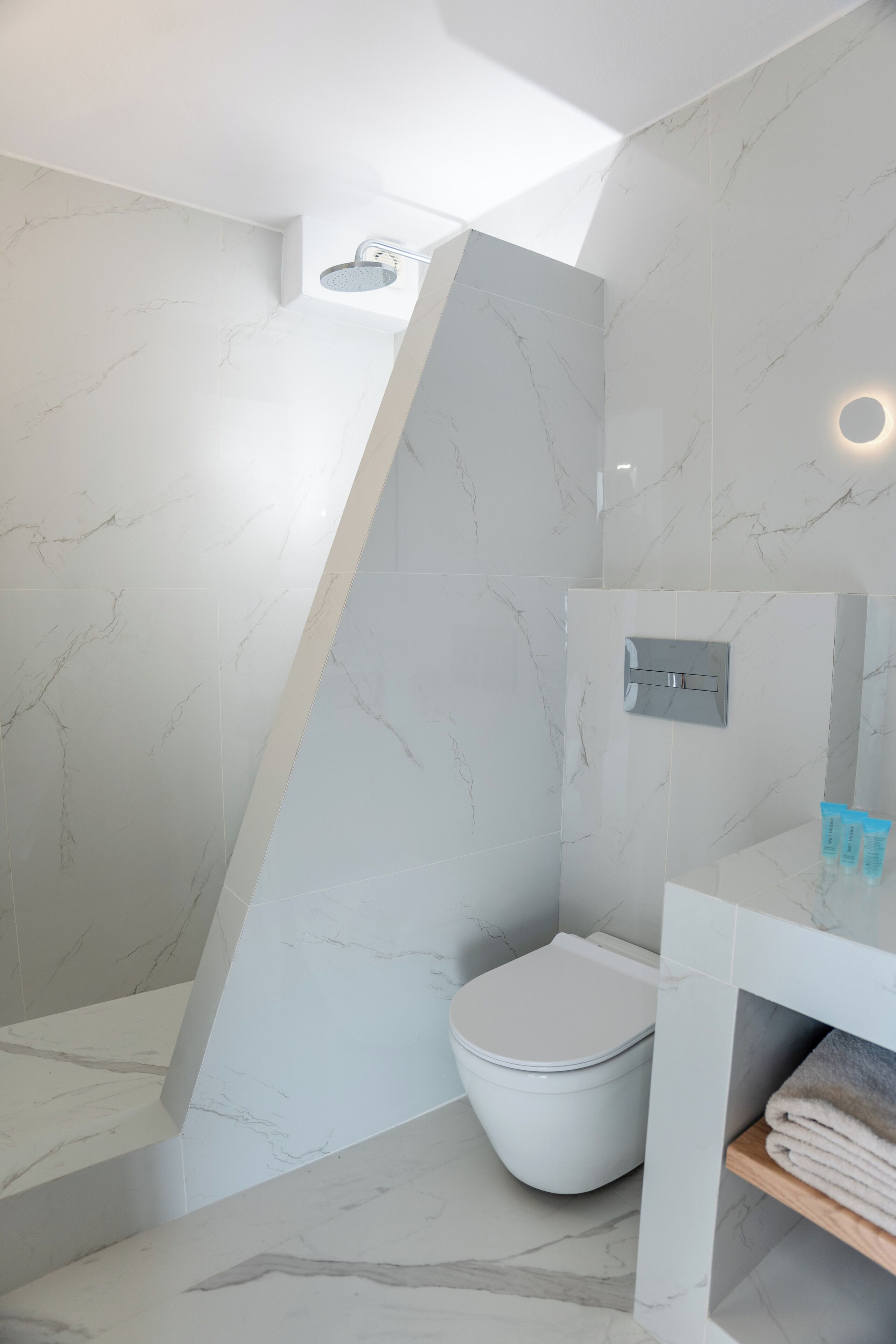 A modern bathroom with a white marble floor, a white toilet, and a shower area.