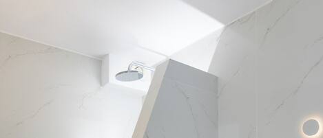 A modern bathroom with a white marble floor, a white toilet, and a shower area.