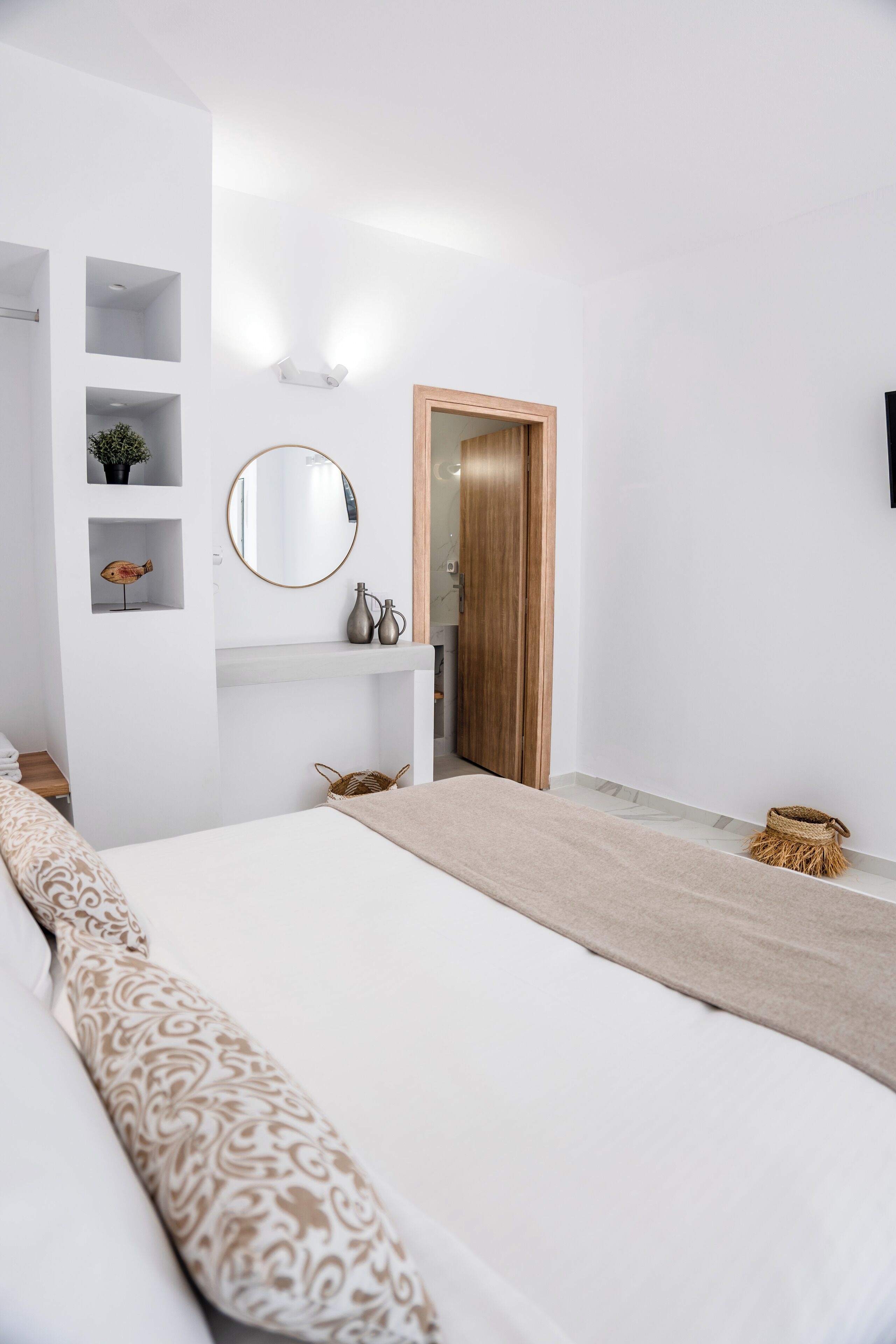 A bedroom with a large bed, a bedside table, a mirror, and a wardrobe.