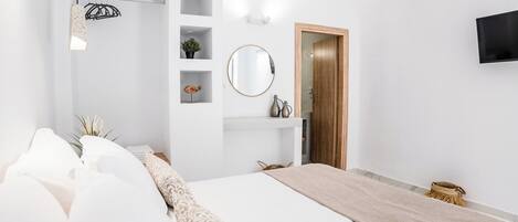 Un dormitorio moderno con una cama grande, una mesita de noche, un espejo y un televisor montado en la pared.