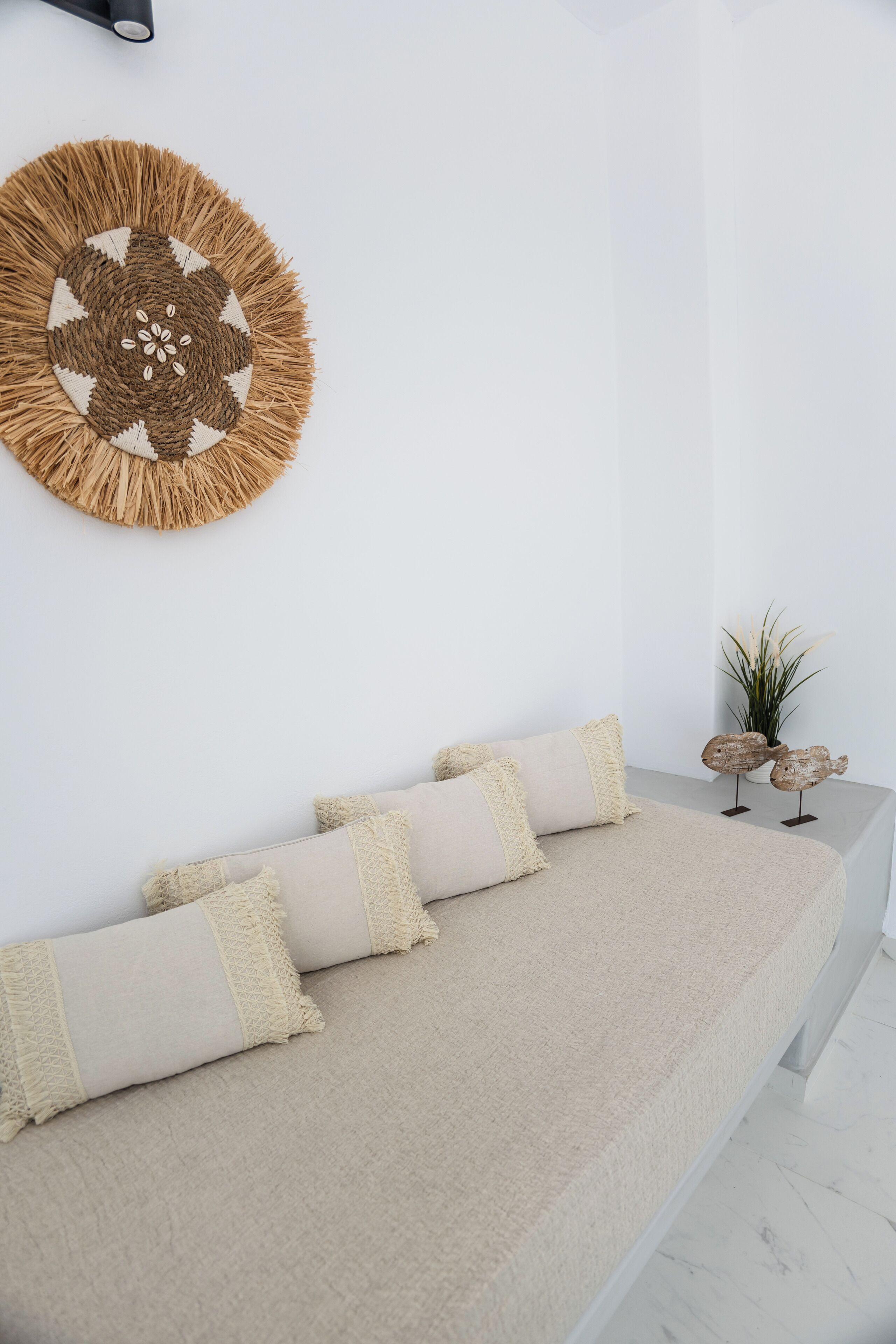 Ein schlichter Raum mit einem beige farbenen Sofa, Wanddekoration und einer kleinen Pflanze.