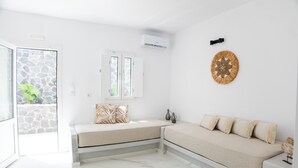 Una habitación moderna y minimalista con pared de piedra, un sofá blanco y un banco.