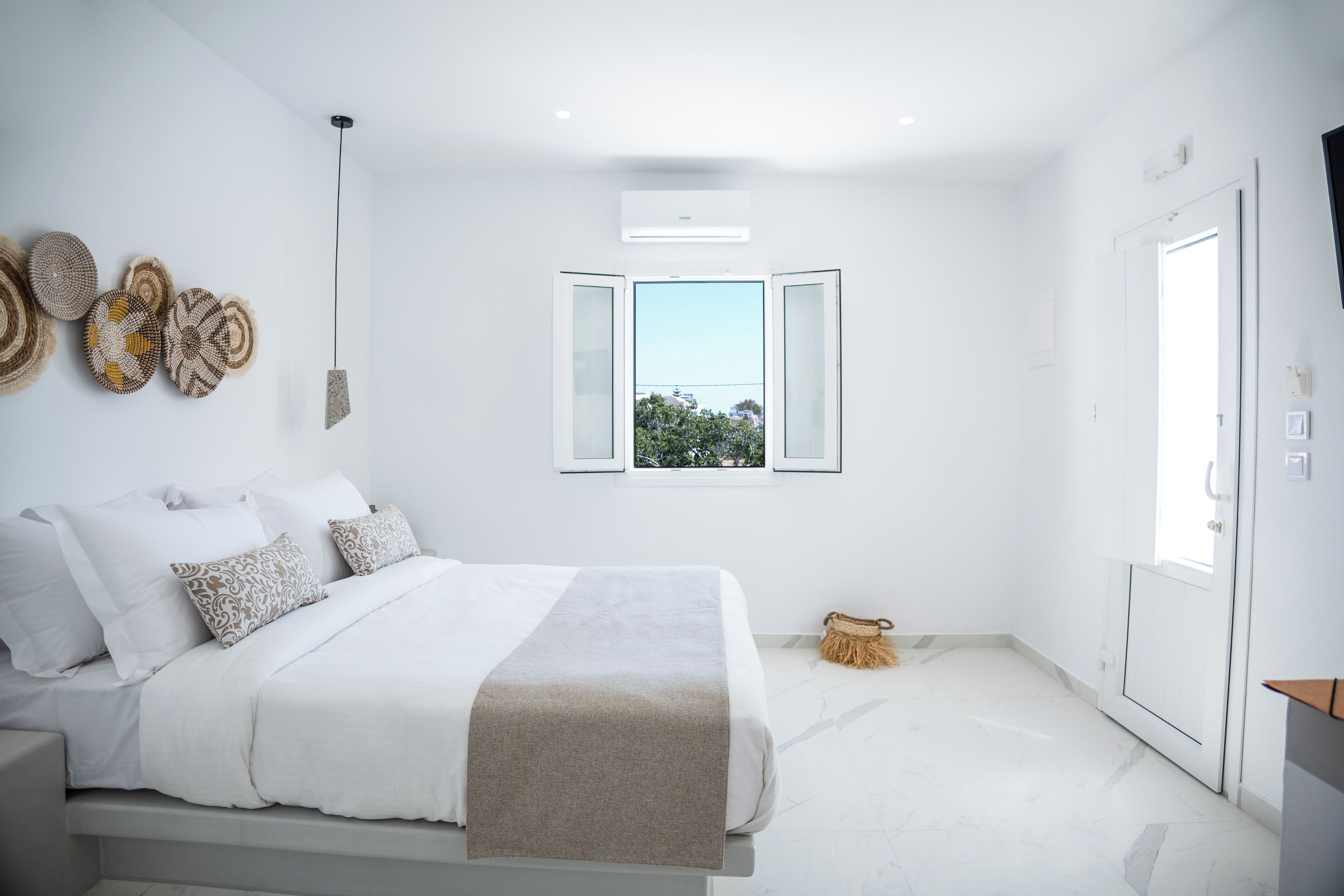 A modern bedroom with a bed, a window, and a wall-mounted air conditioner.