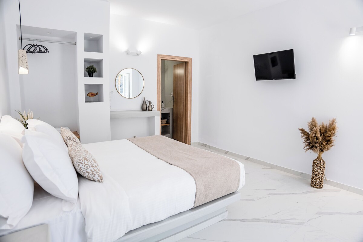 A modern bedroom with a bed, a TV, and a shelf with decorative items.