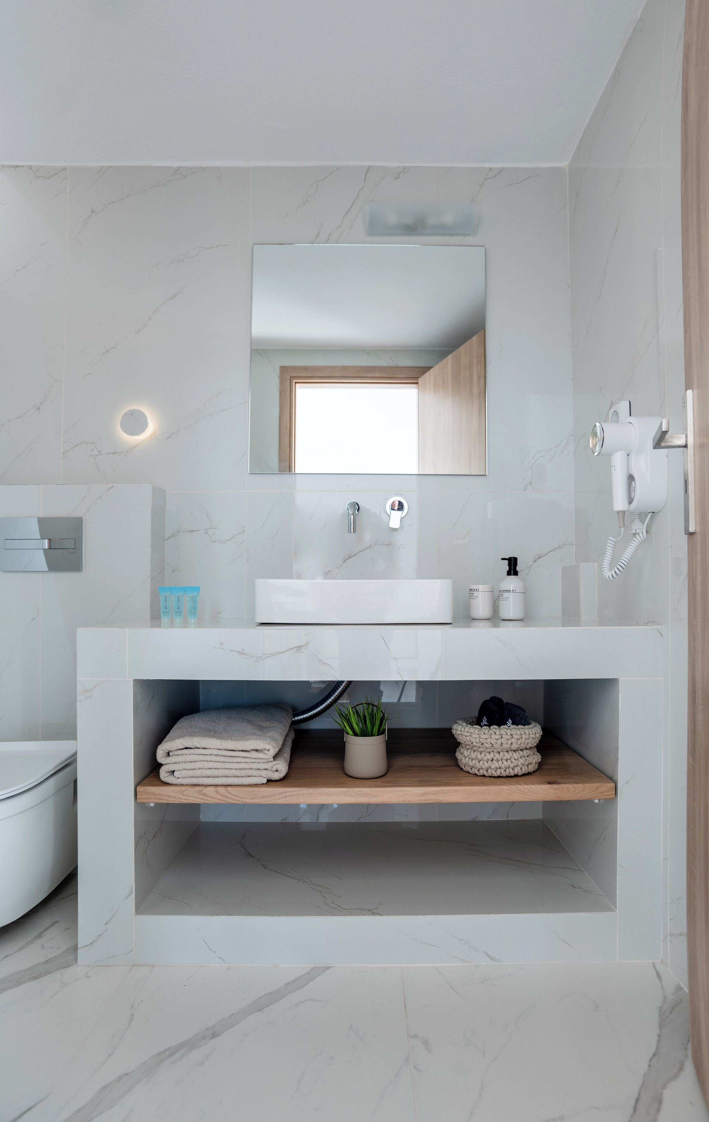 A modern bathroom with a white vanity, a mirror, a built-in sink, and a shower area.