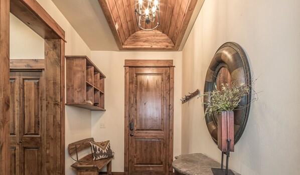 Un intérieur en bois avec un banc, une porte et un miroir fixé au mur.