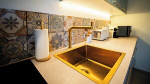 A modern kitchen with a stainless steel sink, patterned backsplash, and a countertop with a toaster and a coffee maker. - 2-person apartment in Conca: Corsican paradise for rent between land and sea (Conca)