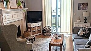 Un salon avec une cheminée, un ventilateur de plafond, un canapé, une table basse et un téléviseur.