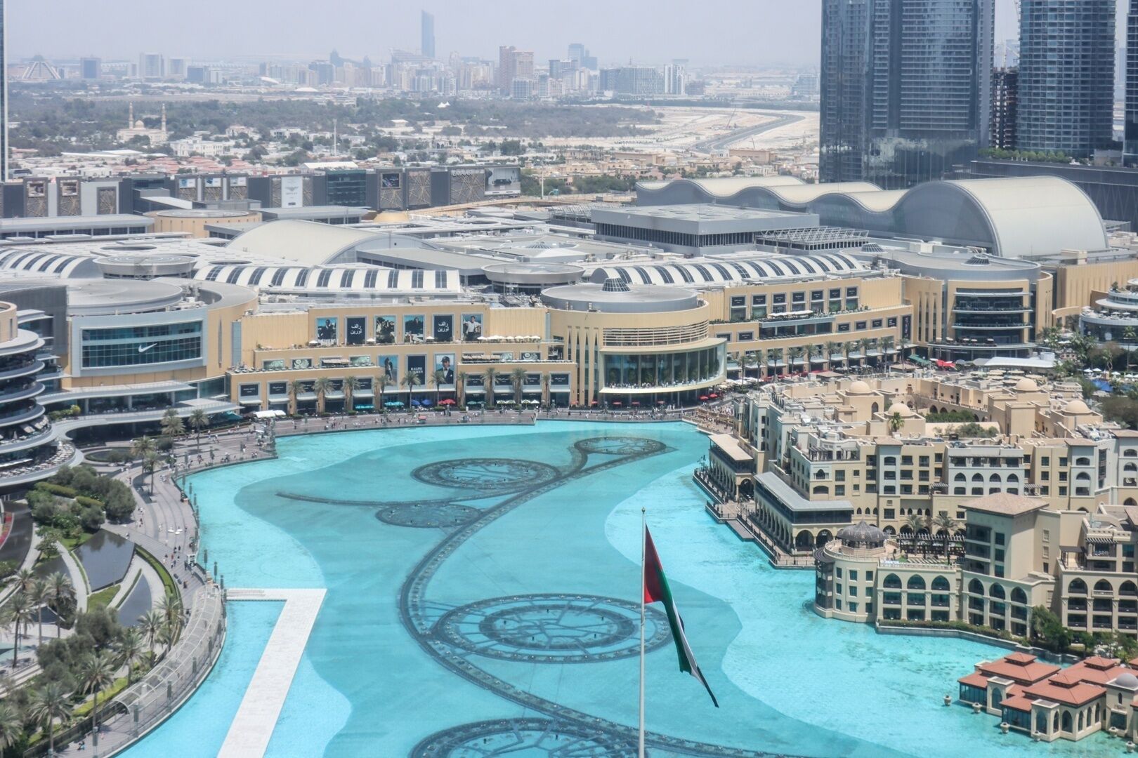 Un hotel grande con un patio central que tiene una piscina e izado de bandera.