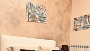 A bedroom with a large bed, white headboard, and a beige wall. There are two paintings above the bed. - MAEL SUPERIOR ROOM (Palermo)
