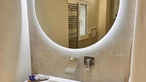 A bathroom with a white sink, a round mirror, and a towel rack. - MAEL SUPERIOR ROOM (Palermo)