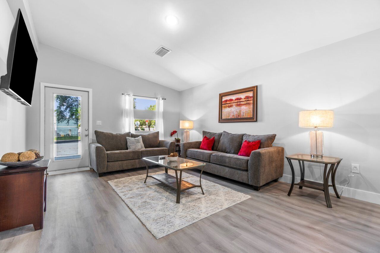 A modern living room with two sofas, a coffee table, a TV, and a painting on the wall.