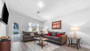 A modern living room with two sofas, a coffee table, a TV, and a painting on the wall.