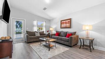 A modern living room with two sofas, a coffee table, a TV, and a painting on the wall.