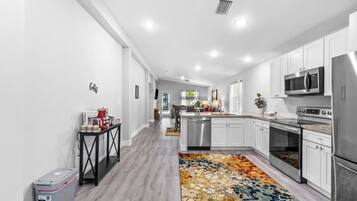 A modern kitchen with white cabinets, stainless steel appliances, and a colorful rug.