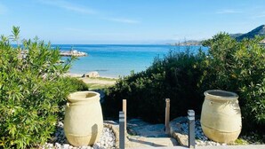 Une vue sur la côte, avec deux grands pots au premier plan, un ciel dégagé et une ligne de côte lointaine.