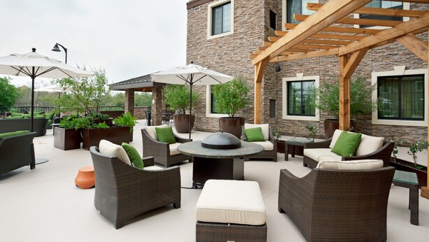 An outdoor patio area with wicker furniture, a round table, and potted plants.