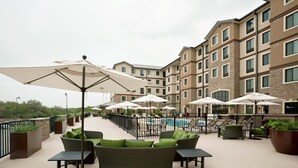 A rooftop patio with outdoor seating, umbrellas, and a swimming pool.